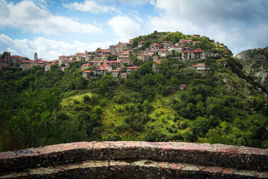 Dimitsana, a picturesque mountain village in Arkadia region, Peloponnese, Greece, nestled on a green hillside with traditional stone houses and red-tiled roofs.