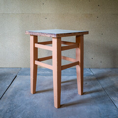 an old stool used during the renovation and construction of a house renovation against the background of a chipboard wall and a concrete floor