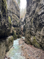 The beautiful stream flows through the rocky valley of Partnachklamm Gorge, where lush moss clings to stones, creating a vibrant and serene natural scene in Garmisch-Partenkirchen.