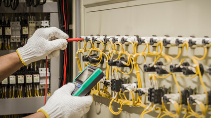 Electrical engineer tests the operation of the electric control cabinet on a regular basis for...