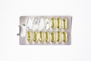 Blister pack with yellow capsules located on a flat surface. Vitamins