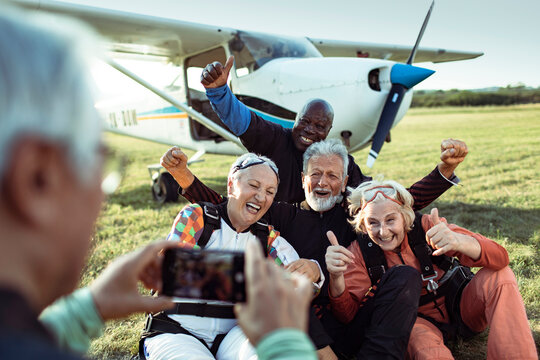 Diverse senior friends taking group photo after skydiving