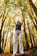 Fototapeta premium Beautiful young redhead woman walking and jogging in the woods with bottle of drinking water. Healthy lifestyle and sport in nature concept.