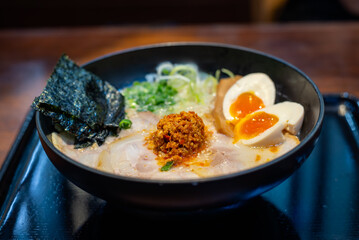 Japanese noodle tonkotsu soup ramen with egg and pork in black ramen bowl for Japanese food style.