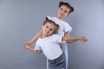 Portrait of cute little sisters on grey background