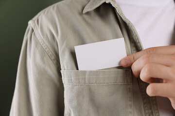 Man taking blank business card from pocket of his jacket on green background, closeup. Mockup for...