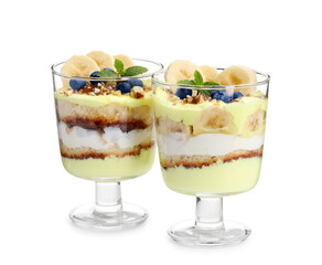 Tasty trifle dessert. Banana, blueberries, sponge cake and whipped cream in glasses isolated on white