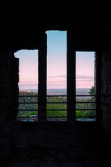 Blick durch ein Fenster in der Burgruine Hohenbaden auf den Sonnenaufgang über dem Rheintal und...