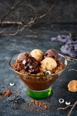 Halloween party chocolate puddings or Panna Cotta with brownie crumbles and chocolate sculls served in clear glass on grey dark background. Party idea for Halloween.