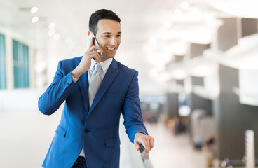 Smiling businessman talking on mobile phone at airport