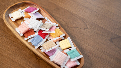 Vibrant Thread Palette: Colorful Embroidery Floss on a Wooden Plate with Copy Space