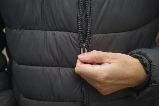 A man zipping up his puffer jacket. Close up.