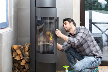 A young man cleans a fireplace to be prepared for the harsh winter during an energy crisis	
