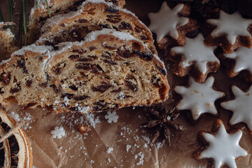 A festive plate featuring traditional German Christmas treats, including slices of Stollen bread filled with dried fruits and nuts, accompanied by star-shaped cinnamon cookies glazed with white icing.