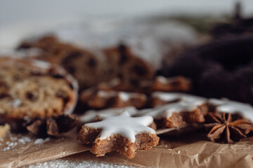 Tangerines and German Christmas pastries, chocolate gingerbread and star-shaped cookies with white icing.Traditional Christmas stollen made of dried fruits and nuts sprinkled with powdered sugar on t