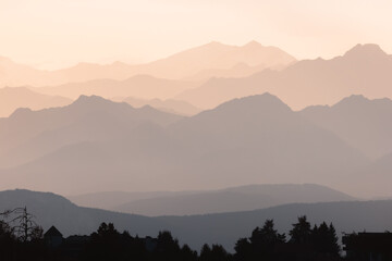 Hazy, layered view of the Italian Dolomites at dawn, with soft light and silhouetted peaks creating a tranquil and atmospheric scene.