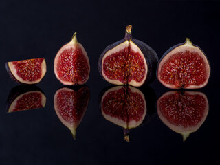 figs a group of fruits cut in half, rich in valuable minerals and nutrients, black background reflected in the base, warm colors, inside of a fig fruit for health