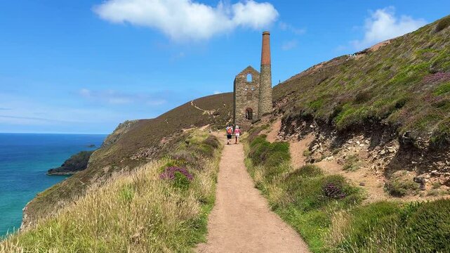 People alking towards the historic Wheal Coates in St Agnes town, Cornwall, England, UK