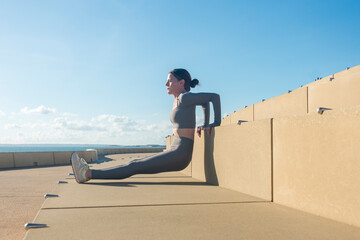 sporty woman doing a reverse push up exercise outdoors