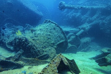 Sunken gun turret resting on ocean floor with marine life