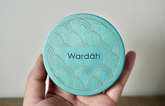 Jakarta, Indonesia - October 24th, 2024 - Hand holding Wardah Exclusive Two Way Cake compact face powder packaging isolated on horizontal ratio indoor environment background.