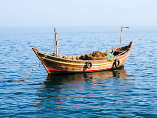 Naklejka premium A boat gently floats on calm water, reflecting the surrounding scenery in a serene setting.