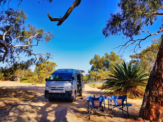 Small motorhome and camping furniture at a beautiful camping spot on the shore of Lake Indoon, shire of Carnamah, west coast of Western Australia.