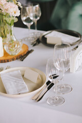 Pastel flowers in glass vases placed on wooden stands. Romantic table decor with flowers and candles for special occasions. Merry decor