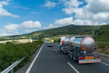 Tanker truck with trailer driving on the highway, with orange plates for dangerous liquids and...
