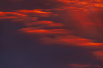 A captivating sky at sunset with dark red and orange clouds, creating a striking and moody atmosphere. The layered clouds add depth and intensity to the scene.