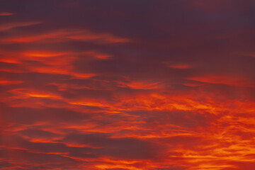 Fototapeta premium A captivating sky at sunset with dark red and orange clouds, creating a striking and moody atmosphere. The layered clouds add depth and intensity to the scene.