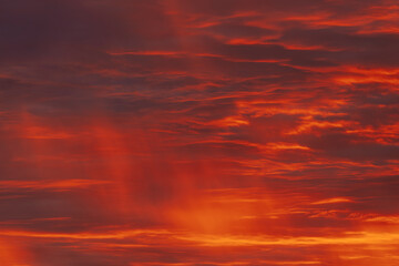 A vibrant, fiery sky with rich red and orange clouds, capturing the dramatic beauty of a sunset....