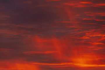 A vibrant, fiery sky with rich red and orange clouds, capturing the dramatic beauty of a sunset. The gradient of colors creates a warm, atmospheric scene.