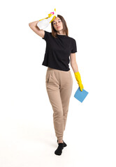 A young woman performs cleaning tasks at home, wearing bright gloves and holding supplies in a well-lit space