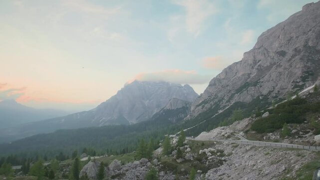 route qui traverse les montagnes des alpes itliennes ( Dolomites) au coucher de soleil avec des couleur orang&eacute;e et un ciel bleu le tout entour&eacute; de montagnes majestueuses