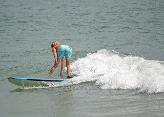 A young man seen from behind, bending over while surfing a wave in the ocean in Florida 