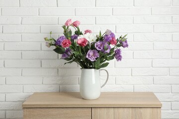 Vase with beautiful eustoma flowers on wooden chest of drawers