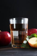 Tasty fresh apple juice in glass and fruits on black wooden table