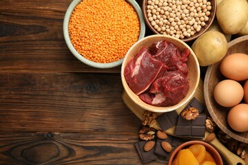 Different products rich in iron on wooden table, flat lay. Space for text