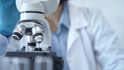 Scientist using microscope in laboratory. Close-up of a researcher's hands adjusting a modern microscope in a lab setting. Science concept