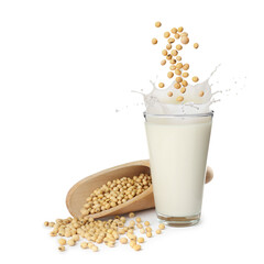 Soy beans falling into glass of plant milk on white background