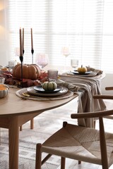 Stylish table setting with beautiful dishware and autumn decor in dining room