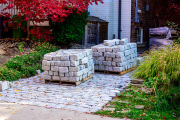 granite paving stones on wooden pallets on an in progress driveway paving project shot in an older...