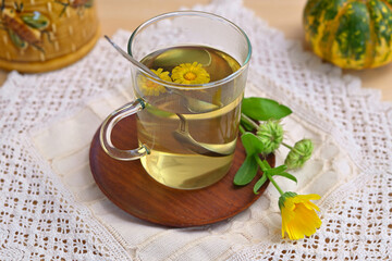 still life with a cup of herbal tea with calendula flowers on the table