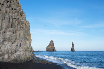 Black basalt cave at the sea in vik, iceland. Two rock formations in the sea. Black beach scenic location. Travel destination