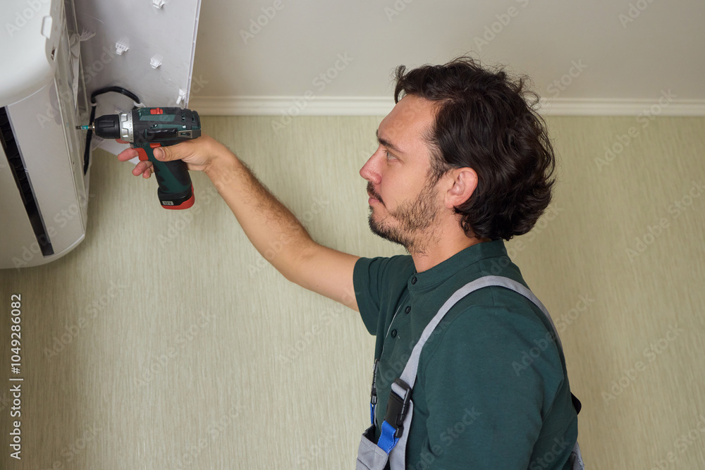 Poster a skilled professional worker is installing a ceiling appliance using a power drill tool
