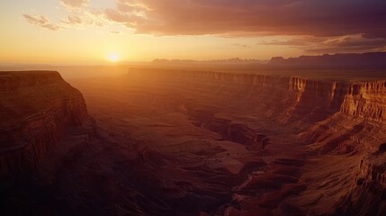 A breathtaking sunset over a grand canyon with layers of rock formations and a hazy sky.