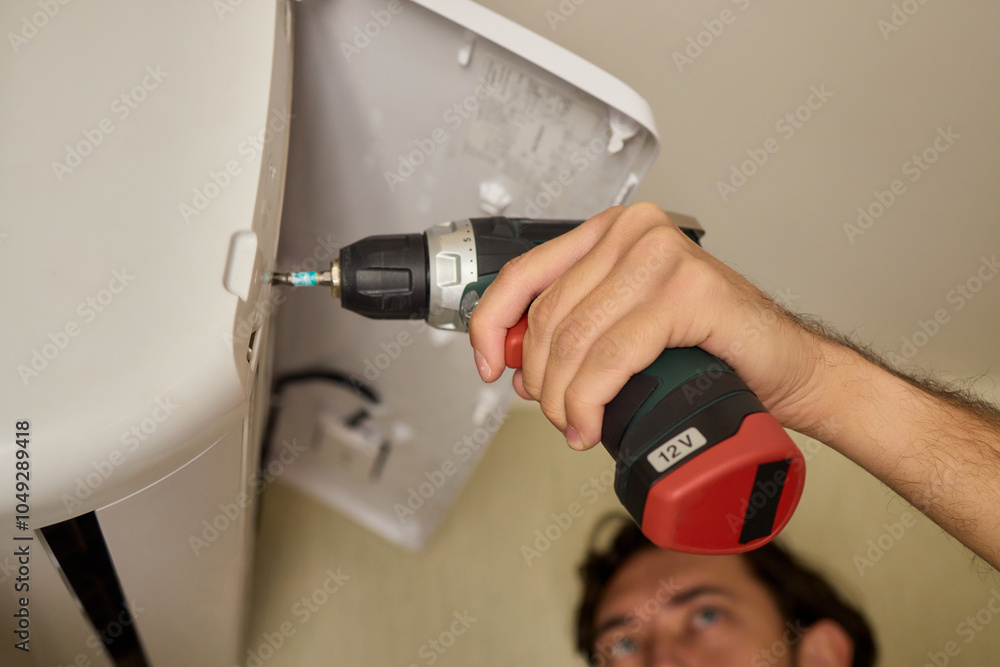 Poster a skilled professional worker is installing a ceiling appliance using a power drill tool