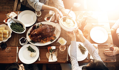 Food, people and eating together at table for holiday celebration or dinner party. Above group of family or friends hands sharing healthy lunch with chicken or turkey, vegetables and wine drinks