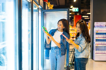 Happy Asian woman family enjoy urban lifestyle shopping together at department store. Mature mother and adult daughter choosing, checking price and buy food and grocery in supermarket at shopping mall